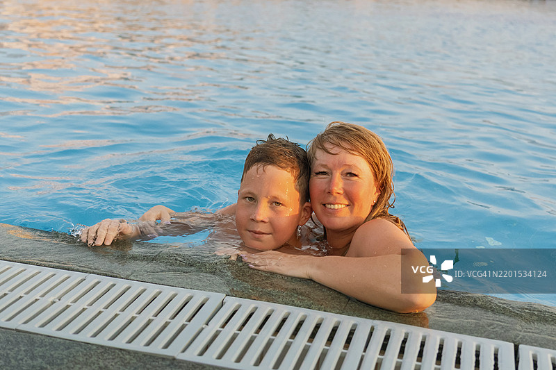 母亲与她10岁的儿子在游泳池中图片素材