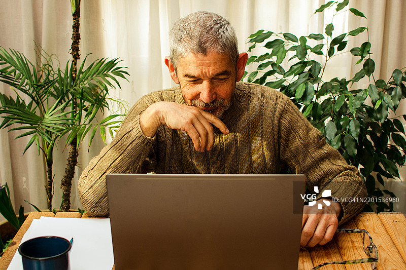 老年男子在家使用笔记本电脑工作图片素材