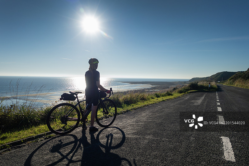 女性骑自行车者俯瞰苏格兰阳光明媚的海岸公路图片素材