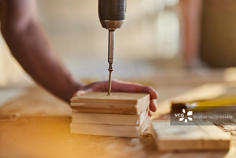 木匠特写镜头，正在将螺丝钻入木材中。图片素材