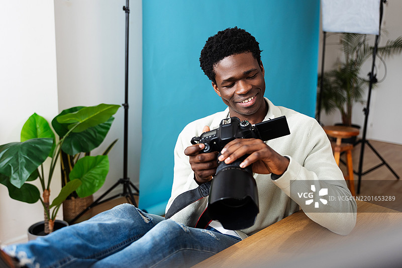 年轻快乐的摄影师在现代工作室里查看相机中的照片图片素材