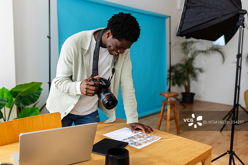 年轻的非洲职业摄影师在现代工作室中查看拍摄情绪板图片素材