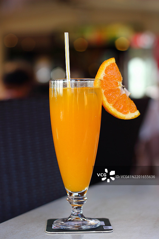 一杯新鲜橙汁，配有一片橙子图片素材