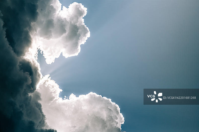 阳光透过壮丽的云层洒在山峰上图片素材