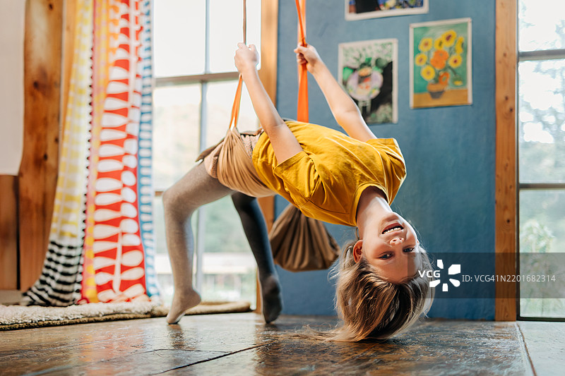 年轻女孩倒挂在秋千上，朝镜头微笑图片素材