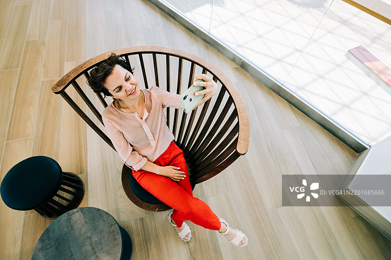 优雅的女性坐在木制扶手椅上自拍图片素材