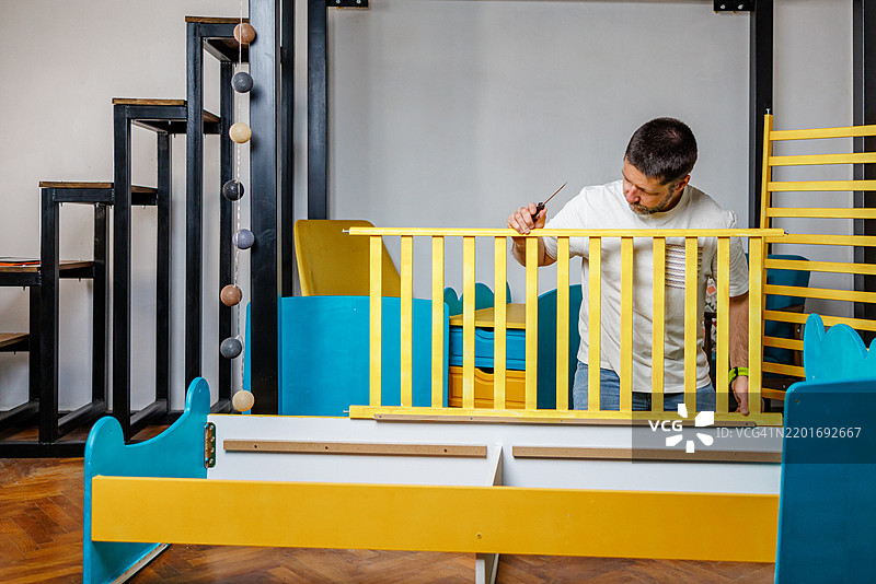 男人为他的新生儿组装婴儿床图片素材