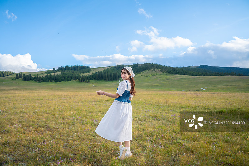 在花田中，女人享受放松、独立和幸福，周围是晴朗的天空、乡村风光和自然泉水的健康氛围。图片素材