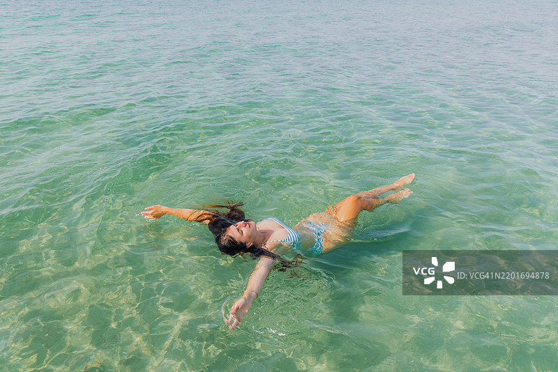 俯瞰一位迷人女性在清澈海水中欣赏海滩度假图片素材