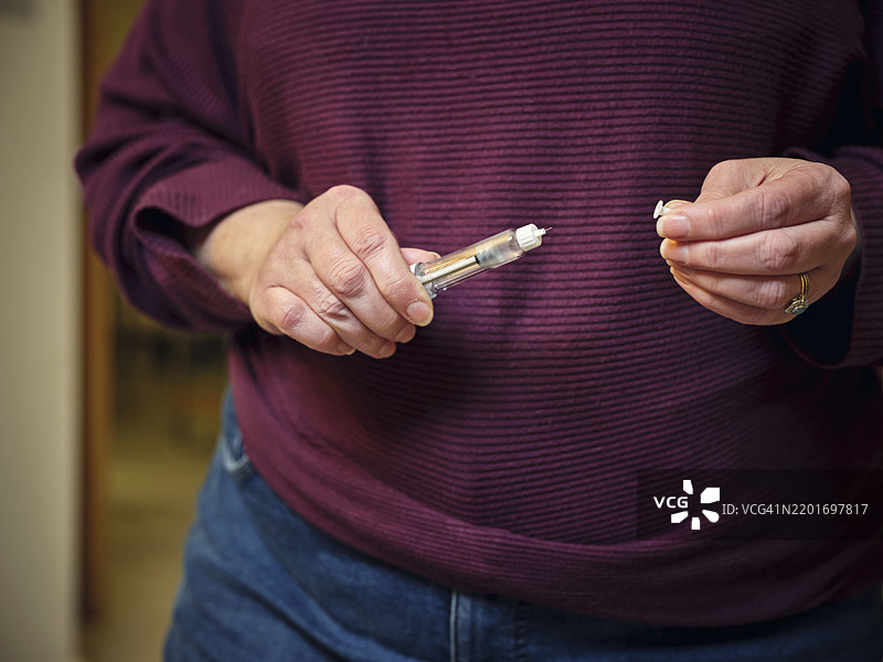 一位女性正在使用赛马鲁肽笔准备进行皮下自我注射，这是一种“减肥药”。这一现代减肥和糖尿病治疗方法突显了她在家中的个人健康护理日常。图片素材