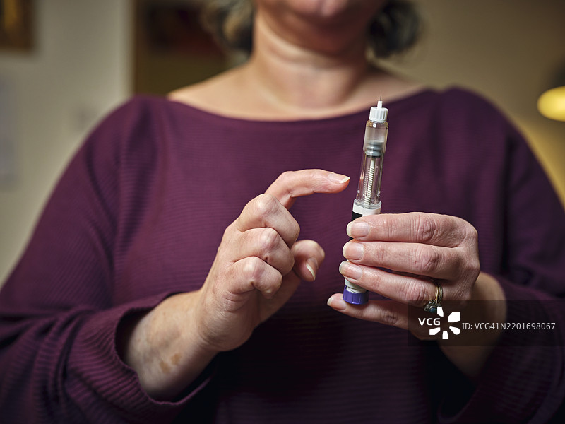 一位女性正在使用赛马鲁肽笔准备进行皮下自我注射。这种现代奇迹的减肥药物和糖尿病治疗药物突显了她在家中的个人健康护理日常。图片素材