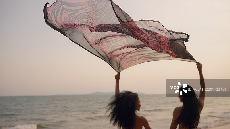 两个年轻朋友在海滩上分享快乐时光，享受他们的假期。图片素材