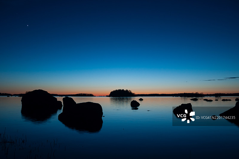 芬兰春季日落后海岸的蓝色海洋，岛屿和岩石。图片素材