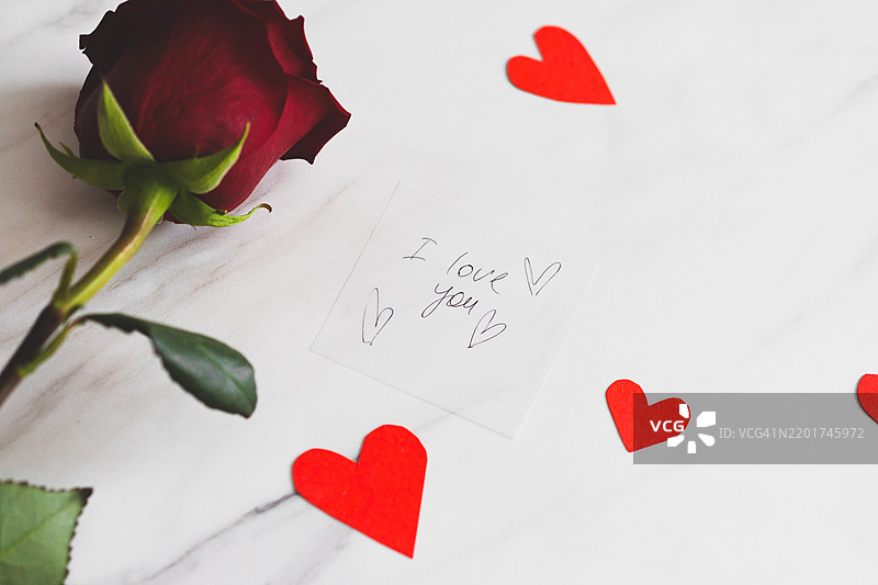 浪漫的信件与玫瑰和心形彩纸洒在大理石桌上，准备迎接一个特别的时刻图片素材