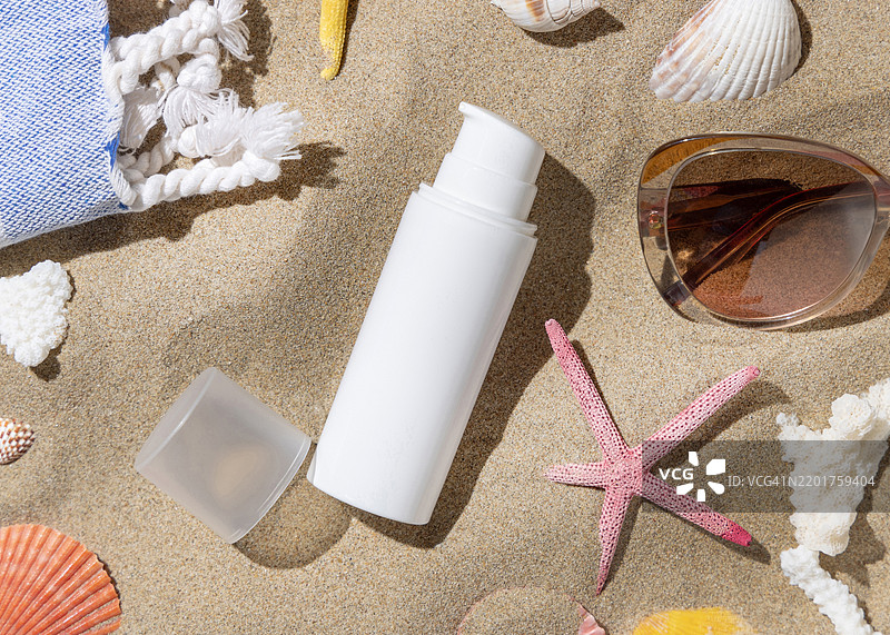 防晒霜瓶靠近毛巾，沙滩上的海星和贝壳俯视图，手影，化妆品展示模版图片素材