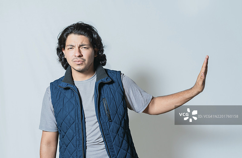 不满的年轻男子用手掌拒绝，独自一人。沮丧的人做出拒绝的手势，眉头紧锁，面露厌恶。图片素材