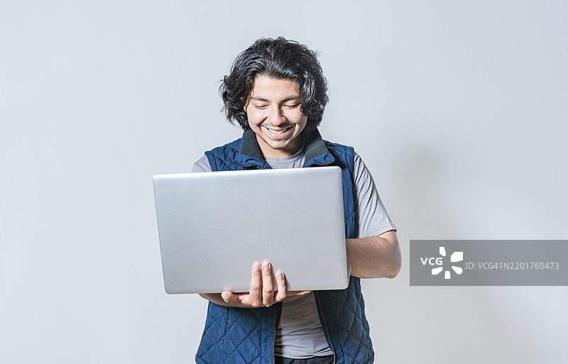快乐的男士在隔离环境中使用笔记本电脑。微笑的帅气男士在隔离环境中查看笔记本电脑上的促销信息。图片素材