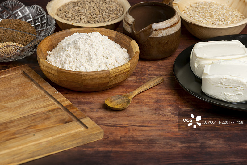 木桌上木碗里的烘焙原料：面粉、干酪和葵花籽图片素材