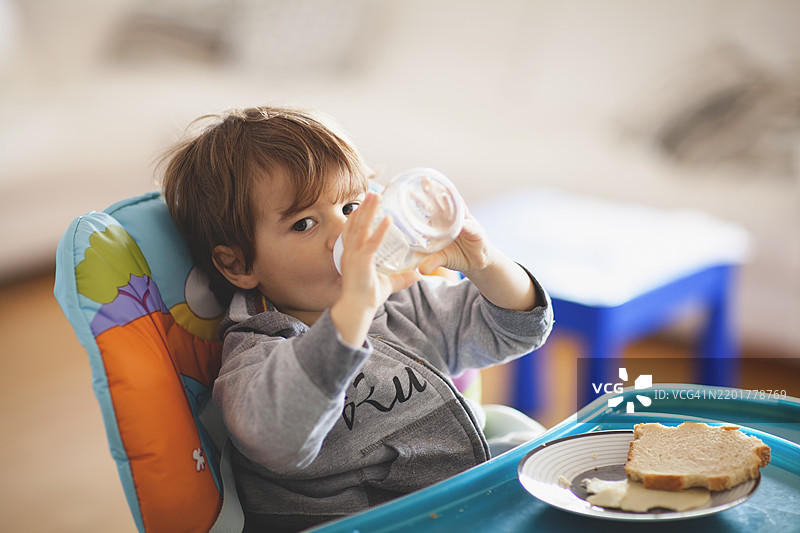 小孩在家里坐着享受零食和饮料图片素材