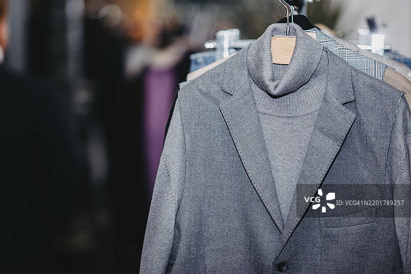优雅的灰色西装挂在衣架上，整齐地展示出时尚的中性色调图片素材