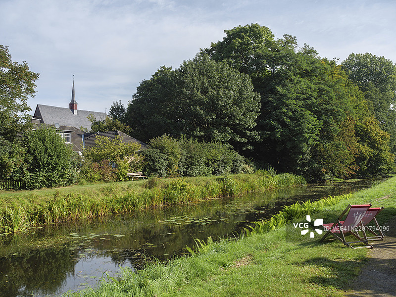 宁静的河流、草地和背景中的教堂，位于德国下莱茵的马里恩塔尔图片素材