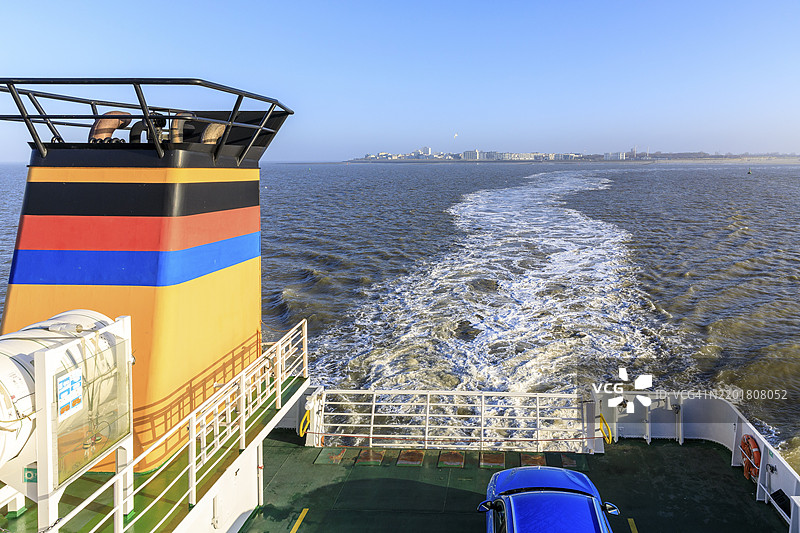 弗里西亚 II 渡轮从诺德奈到诺德迪赫莫尔，背景是下萨克森州诺德奈的轮廓，德国，欧洲图片素材