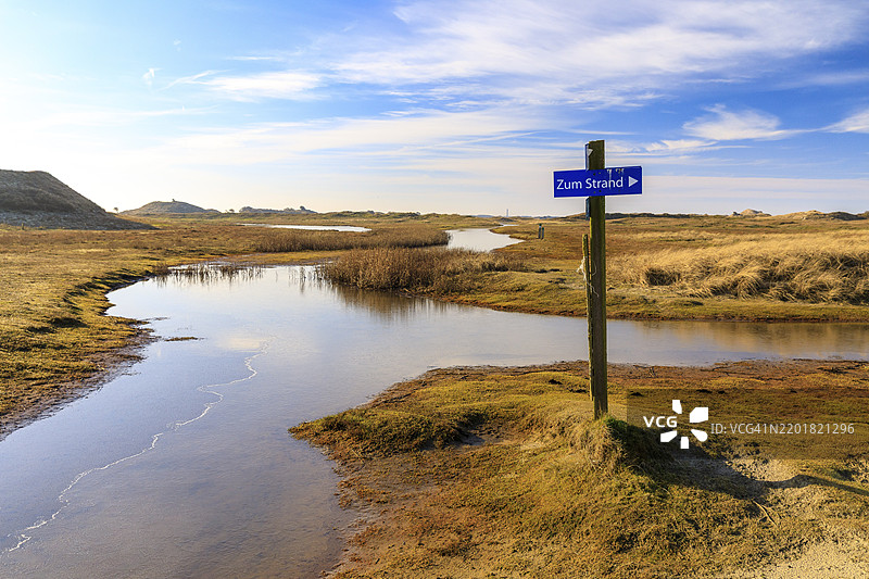 在德国下萨克森州诺德尔奈的波斯特贝克，沙丘景观中的人行道已被地下水转变为湖泊。图片素材