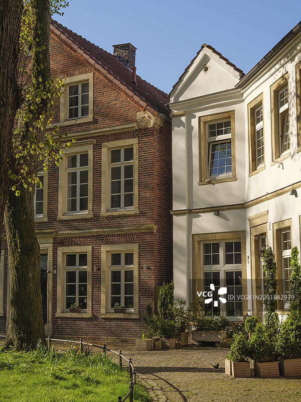 迷人的历史砖砌建筑,明亮的内 courtyard,绿草如茵的草坪和树木,比勒费尔德,北莱茵-威斯特法伦,德国,欧洲图片素材
