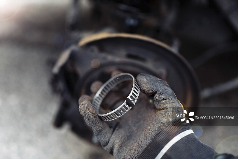 机械师在修理汽车轮胎时手持齿轮部件图片素材