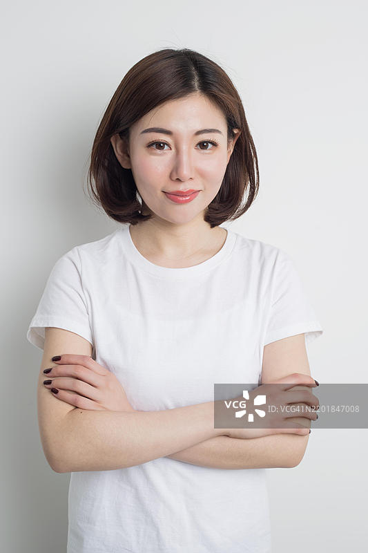 一位年轻的亚洲女性，短棕色头发，穿着白色T恤的肖像。图片素材