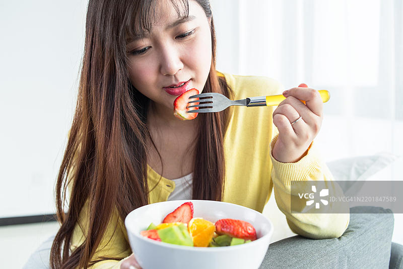 亚洲女性用叉子吃健康的水果沙拉图片素材