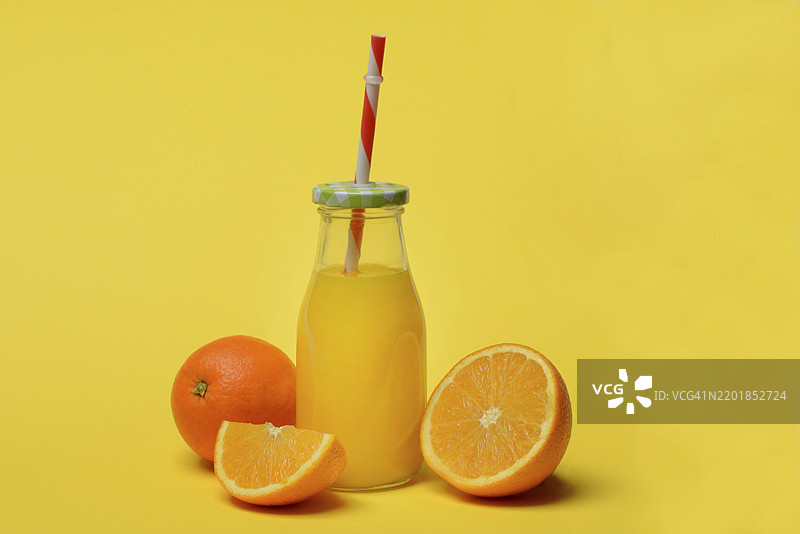 瓶装橙汁和橙子，黄色背景图片素材