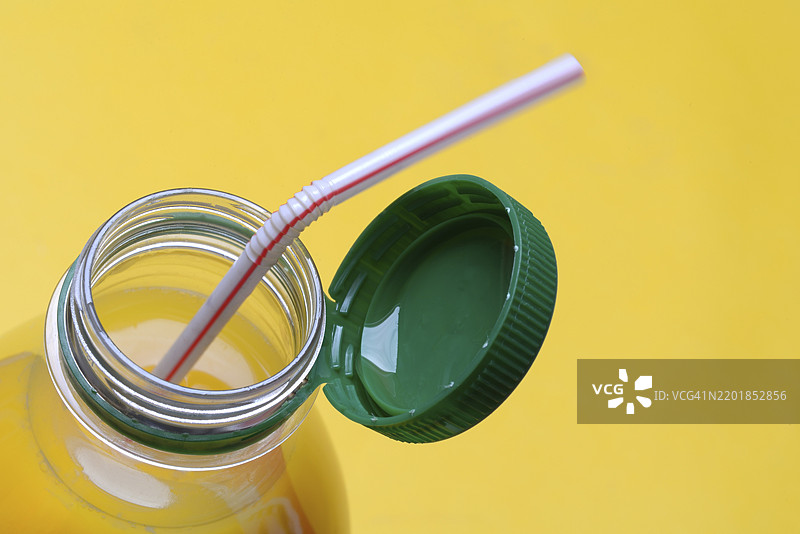 塑料瓶装的橙汁，带有瓶盖和吸管图片素材