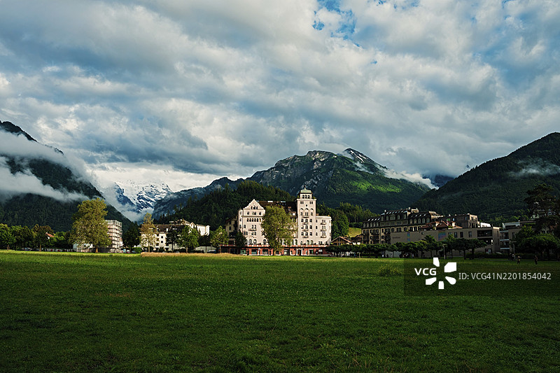 被戏剧性云彩和郁郁葱葱的山脉衬托的历史建筑，城市，村庄，城市风景，街道，古老建筑，古老房屋，瑞士因特拉肯，欧洲图片素材