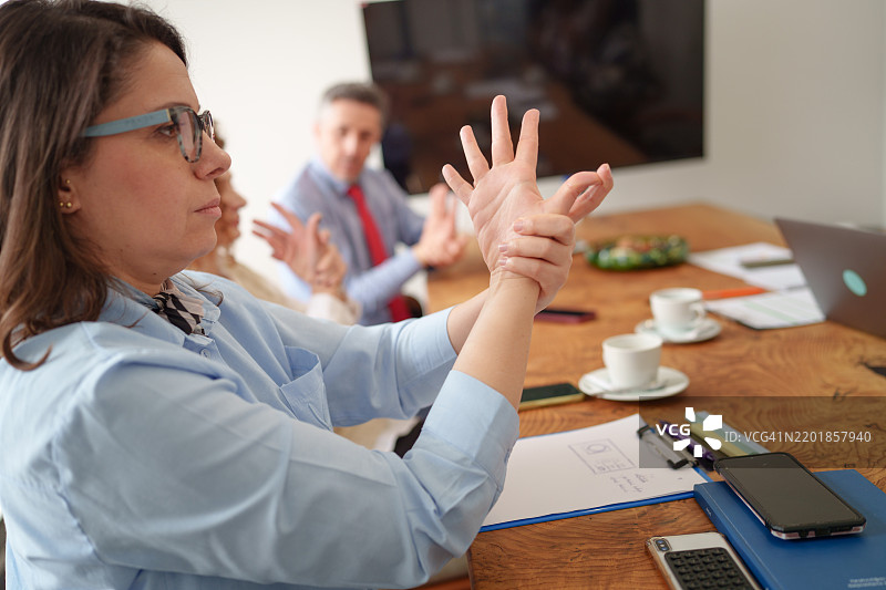 一群多样化的人在会议室中放松手臂。图片素材
