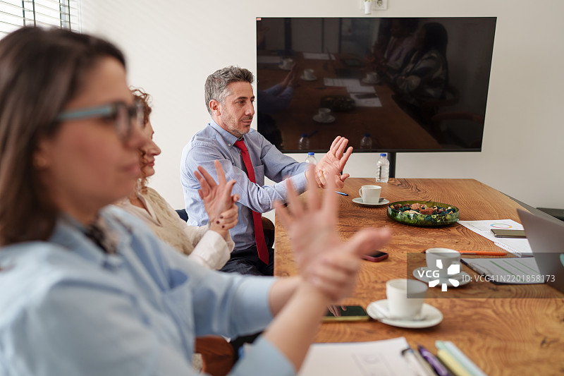 一群多样化的人在会议室里，放松着手臂。图片素材