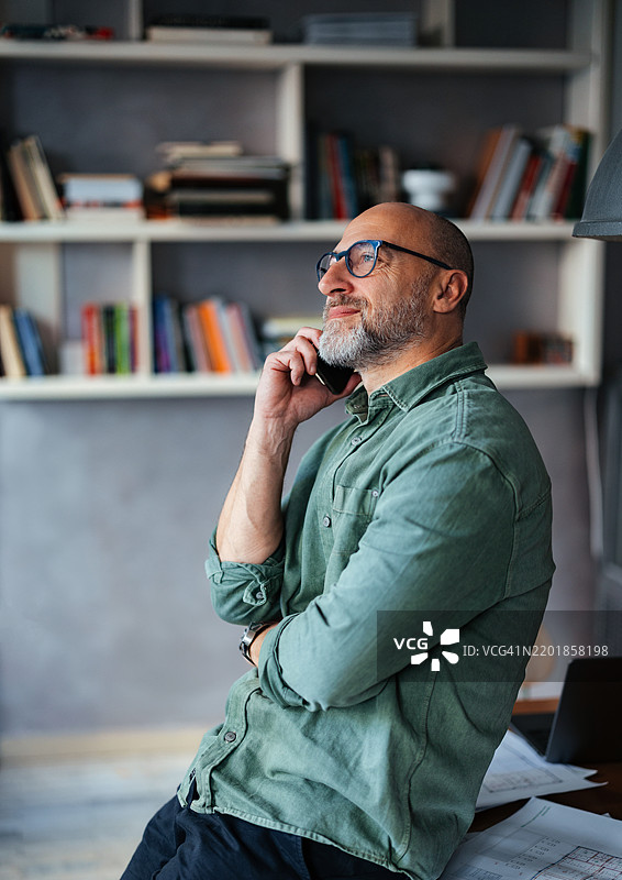 专业男士在舒适的办公室环境中进行电话交谈图片素材