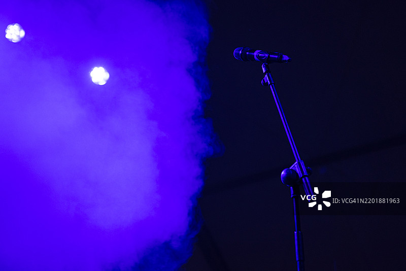 舞台上的麦克风，蓝色灯光和雾效。音乐会、表演、烟雾、派对、歌手、音乐和声音。图片素材