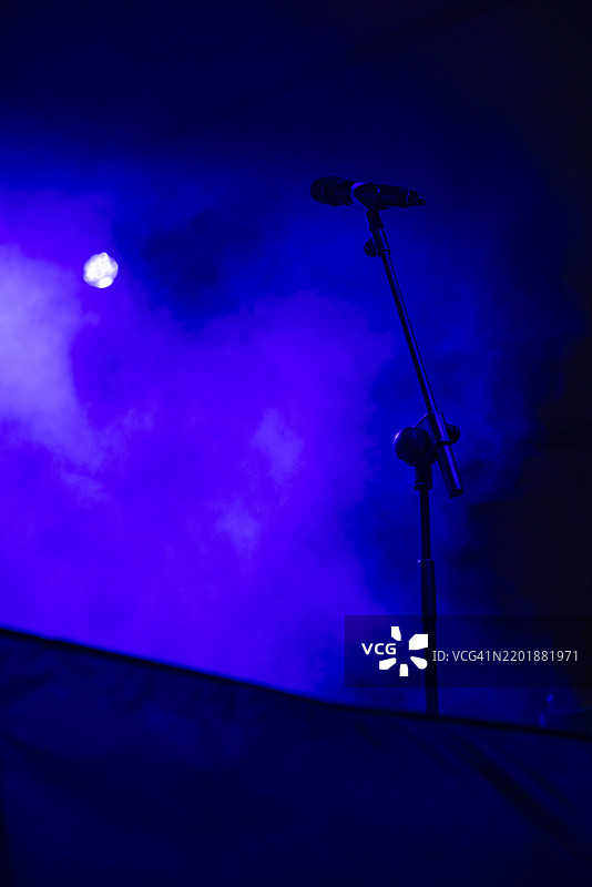 舞台上的麦克风，蓝色灯光和雾效。音乐会、表演、烟雾、派对、歌手、音乐和声音。图片素材