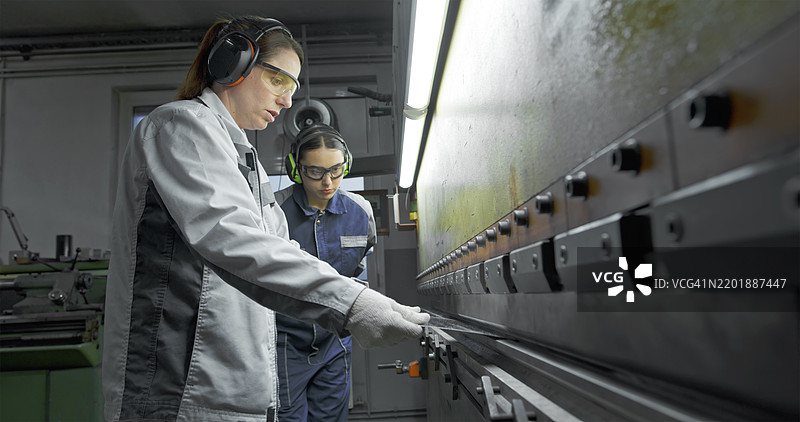 女性技术人员在工厂车间操作金属折弯机图片素材