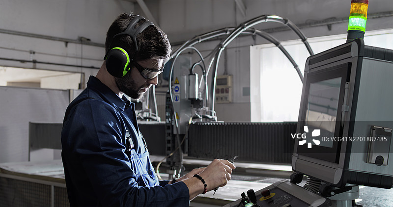 男性技术员在制造厂操作数控水刀切割机图片素材
