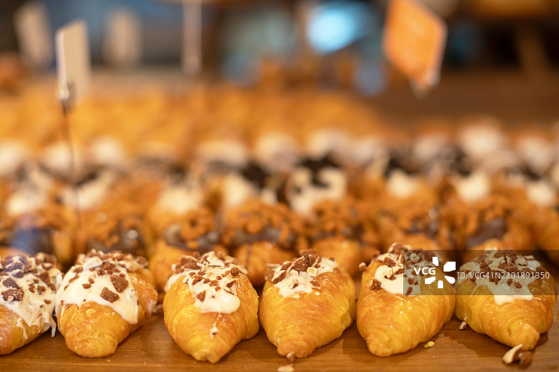 一盘小巧的可颂面包，上面装饰着巧克力和奶油，陈列在咖啡馆里。图片素材