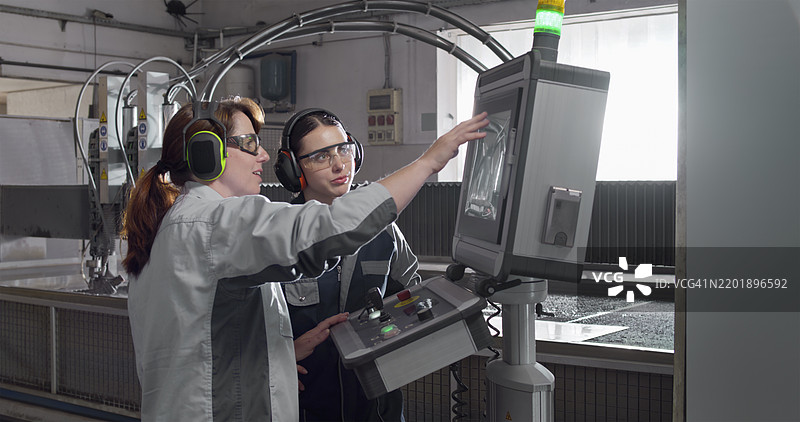 中年女性在水切割机上指导年轻女性图片素材