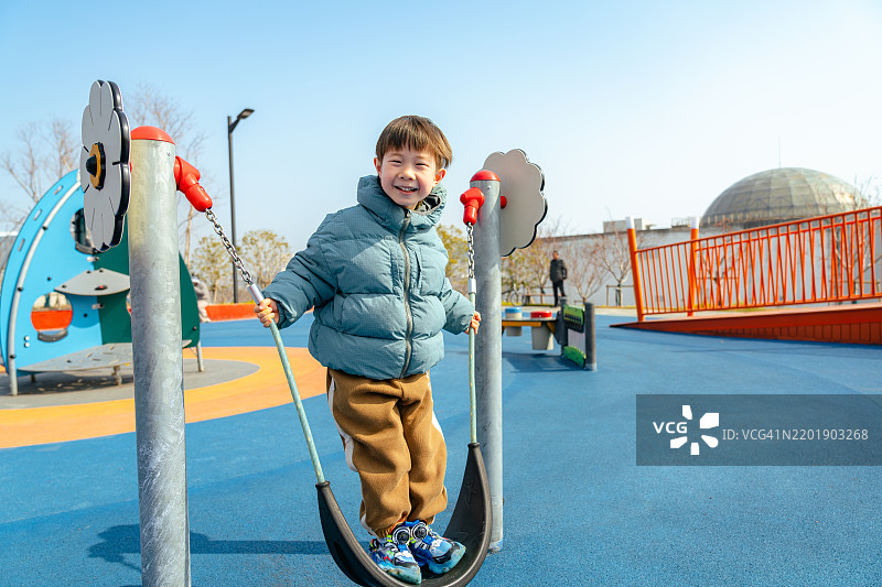 一个可爱快乐的男孩在秋千上玩耍的肖像图片素材