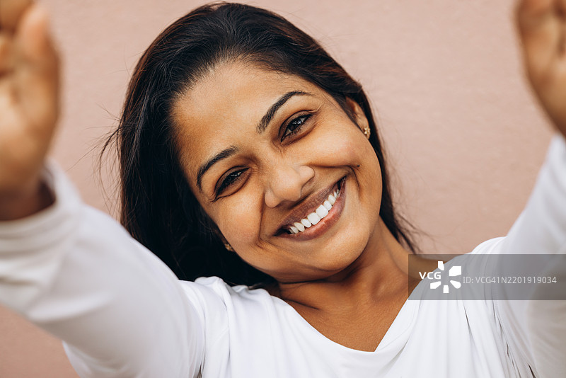 微笑的女性穿着白衬衫，双臂伸展，表现出快乐的姿态图片素材