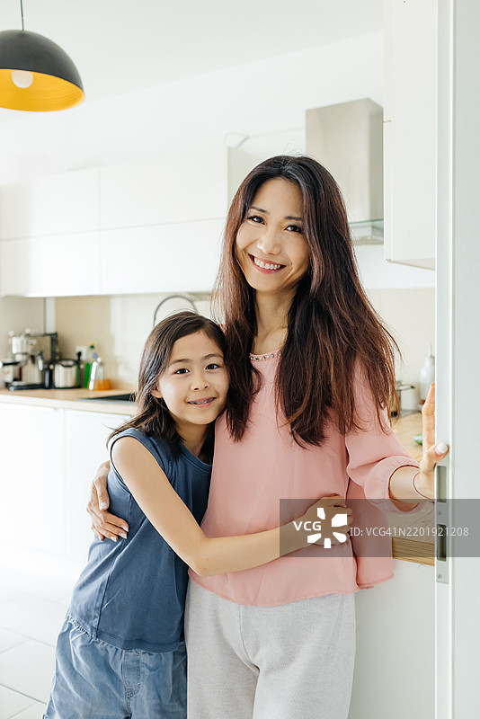 母女在厨房里温暖相拥的亲密肖像图片素材