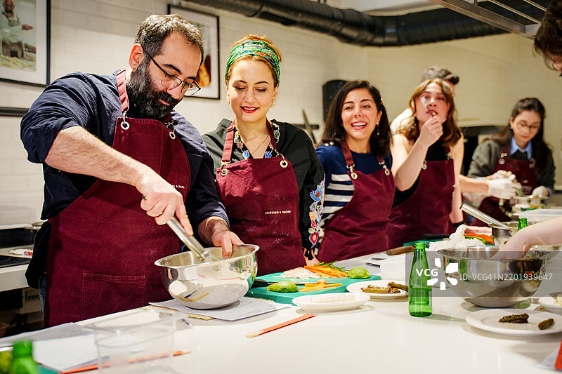 一群穿着围裙的多元化个体在动手烹饪课上仔细制作寿司卷图片素材