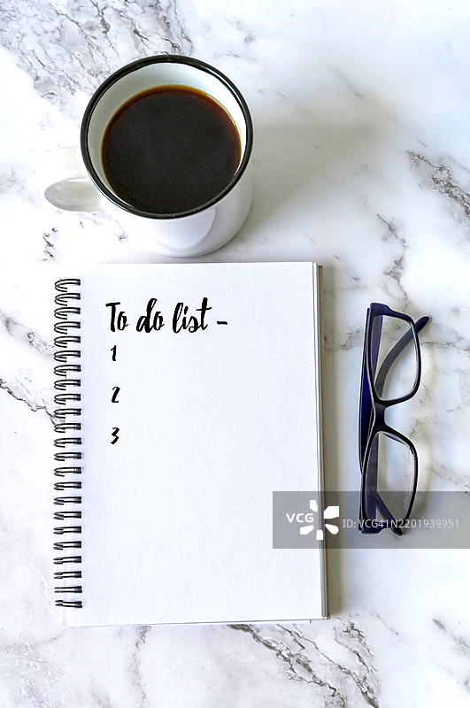 在一张古朴的大理石桌子上放着写有“待办事项”的记事本图片素材