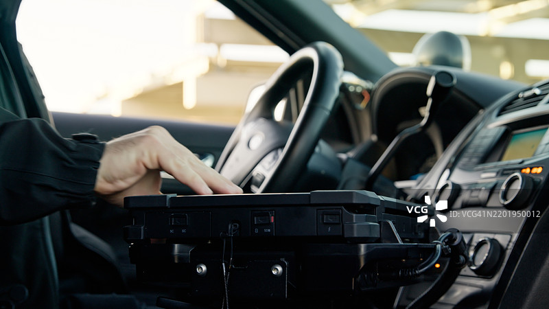 警察上车并伸手拿起笔记本电脑图片素材