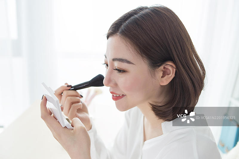 亚洲女性在镜子前化妆图片素材
